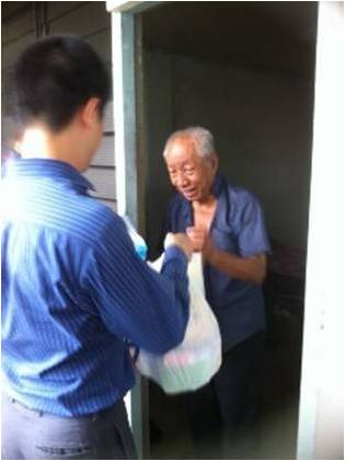 A CNB officer cheerfully distributing goodie bags to an elderly beneficiary of the Lion Befrienders Service Association