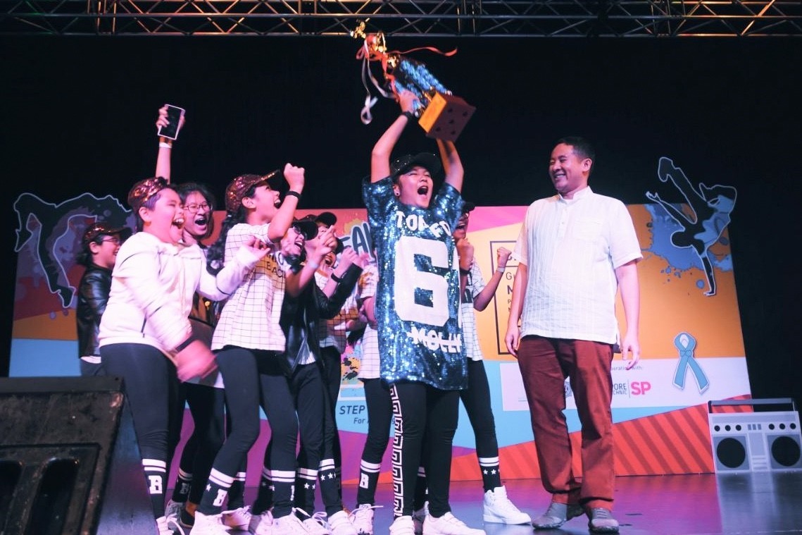 Photo 1: Palm View Primary Modern Dance celebrating their win onstage with Parliamentary Secretary Mr Amrin Amin