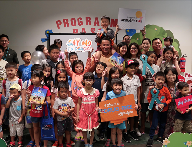 Photo-2 (CNB): Mr Amrin Amin together with parents and their young, enjoying the story-telling  by Ms Jillian Khoo, author of the illustrated book ‘Captain Drug Buster vs Dr Wacko – The Final Showdown’